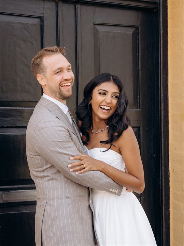 Bride and groom laughing in front of a black door