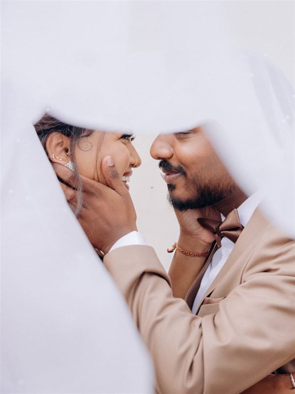 Bride and groom close together behind a veil