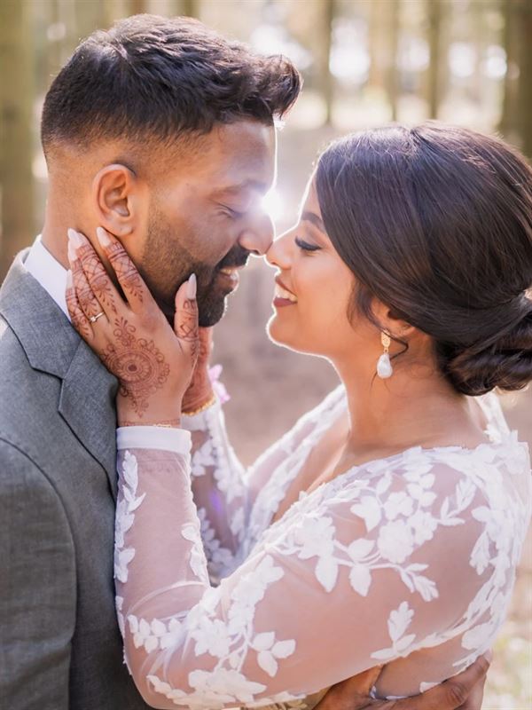 Bride and groom nose to nose in a sunlit forest